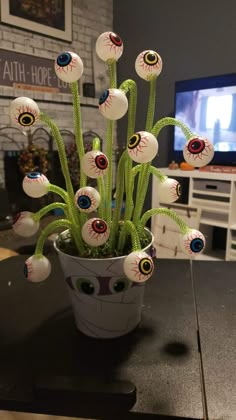 a potted plant with fake eyes and balls in it sitting on a table next to a tv