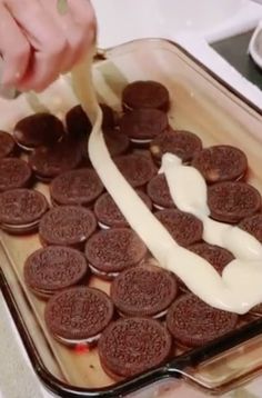 someone is spreading cream on top of oreos in a baking dish with a spatula