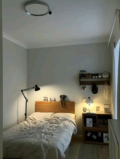 a bedroom with a bed, lamp and shelves on the wall in front of it