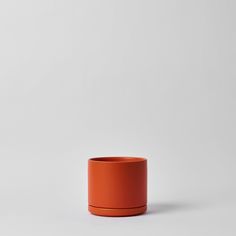 an orange cup sitting on top of a white table