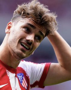 a close up of a soccer player holding his head in one hand and looking off to the side