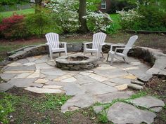 an outdoor fire pit with chairs around it