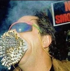 a man with his mouth open and sunglasses on, holding up some spikes to his face