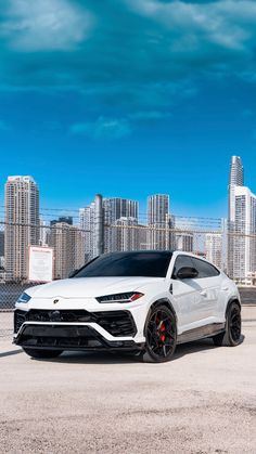 a white lamb suv parked in front of a cityscape with skyscrapers behind it