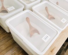 several plastic containers filled with sand and wooden spoons