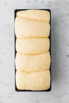 four uncooked dough rolls in a black pan