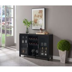 a black cabinet with wine glasses on it and a potted plant next to it