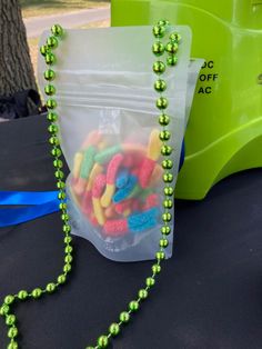 a plastic bag filled with green beads next to a string of neon colored beads on a table