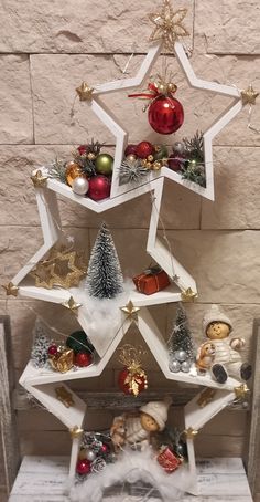 a christmas tree with ornaments hanging from it's sides in front of a brick wall