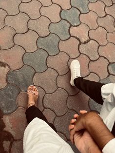 two people sitting on the ground with their feet crossed and one person standing next to them