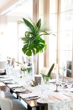 a dining table set up with place settings and flowers in vases on each side