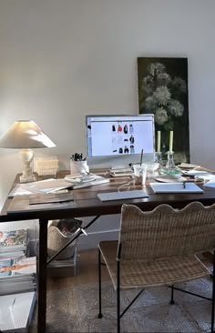 a desk with a computer on top of it next to two chairs and a lamp