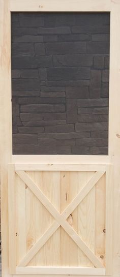 a wooden door with a black brick wall behind it