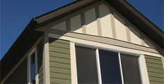 the top of a house with two windows and a cat sitting in the window sill