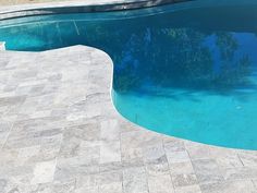 an empty swimming pool in the middle of a patio with stone pavers around it