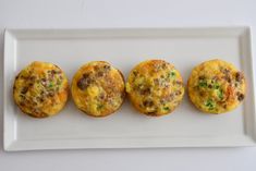 three mini muffins on a white plate with green onions and sausage in the middle