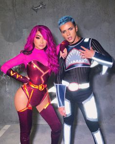 two people in costumes standing next to each other and one is wearing a purple wig