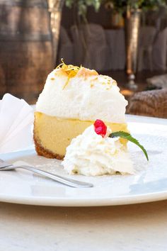 a piece of cheesecake on a white plate with a fork and napkin next to it