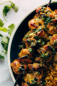 a bowl filled with chicken and rice next to cilantro garnishes