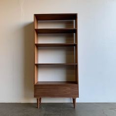 a wooden bookcase against a white wall