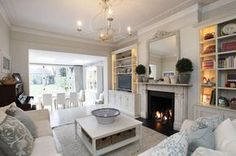 a living room filled with furniture and a fire place under a chandelier in front of a fireplace