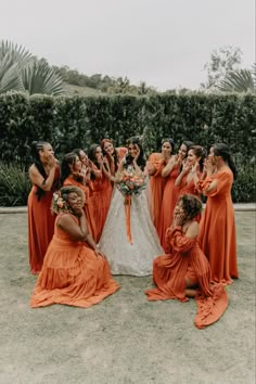 a group of women in orange dresses standing around each other