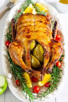 a whole chicken on a platter with vegetables and olives, ready to be served