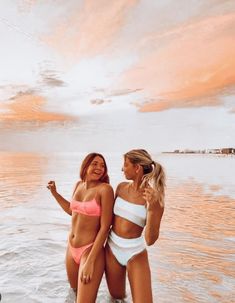 two beautiful women standing in the water near each other