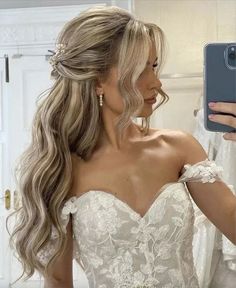 a woman taking a selfie with her cell phone in front of her wedding dress