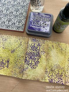 some crafting supplies are laying out on a wooden table next to a bottle of ink