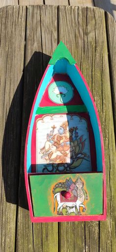 there is a colorful boat with pictures on the front and bottom part, sitting on a wooden dock