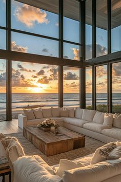 a living room with couches and large windows overlooking the ocean at sunset or sunrise