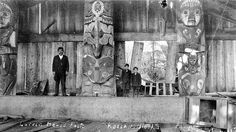 black and white photograph of men standing in front of art work on the side of a building