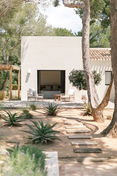 a white house surrounded by trees and plants