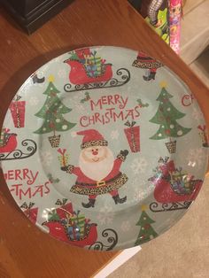 a plate decorated with santa clause and christmas trees on it, sitting on a table