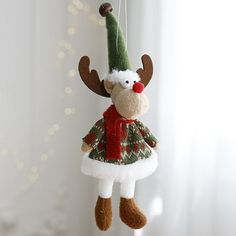 a christmas ornament hanging from a string with a reindeer wearing a green hat and red scarf