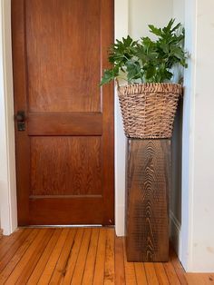 a wooden door with a basket on the floor next to it and a potted plant