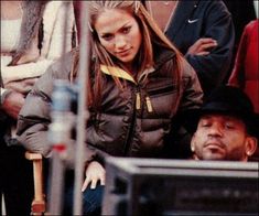 a woman in a black jacket and hat sitting next to a man