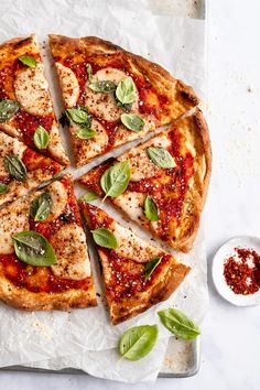 a pizza cut into eight slices with basil leaves on top and sauce in the middle