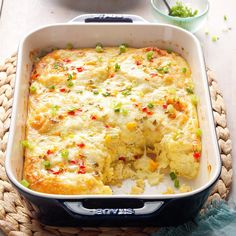 a casserole dish with vegetables and cheese in it sitting on a placemat