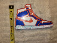 an orange and blue shoe is next to a measuring tape on a white fur surface