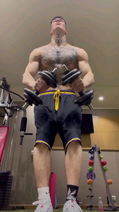 a man standing in front of a gym machine with his hands behind his back and looking up