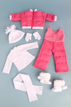 doll clothes and accessories are laid out on a table, including a baby's outfit