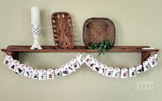 a shelf with some cards hanging from it's sides next to a basket and candle