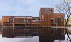 the building has wooden slats on it's sides and is reflecting in the water