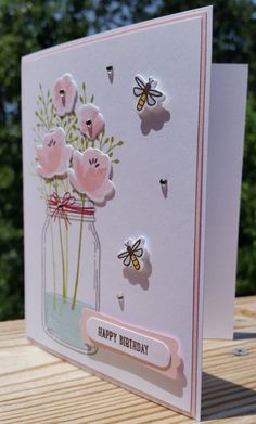 a birthday card with flowers and butterflies in a mason jar on a wooden table outside