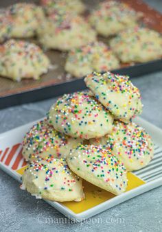 white frosted cookies with colorful sprinkles on a yellow and white plate