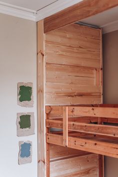 a wooden bunk bed sitting next to a wall with paint swatches on the walls