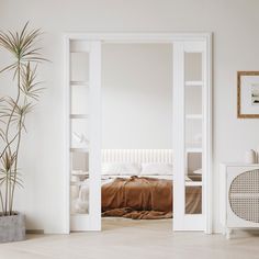 an open door leading to a bedroom with a bed in the corner and potted plant next to it