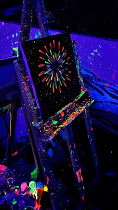 an easel with paint splattered all over it in front of a purple background